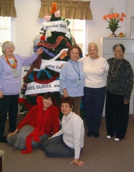 Seniors displaying hand knit scarves and hats they made for the Holiday Coalition